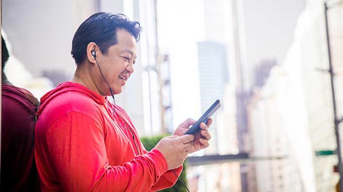 Diverse man using smartphone with headphones