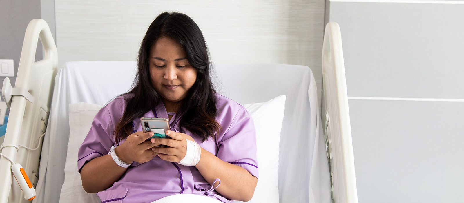 female patient in hospital bed viewing phone